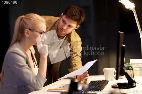 Image of business team with papers working late at office