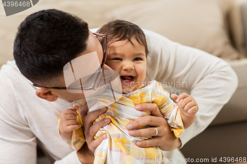 Image of happy father kissing little baby daughter at home