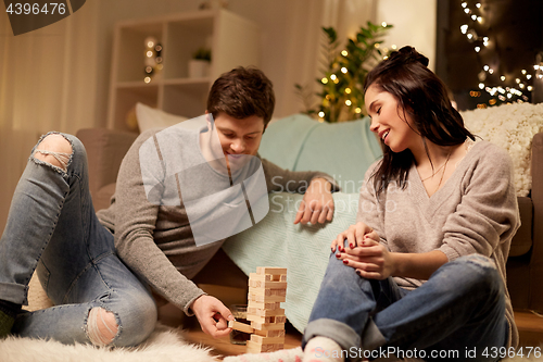 Image of happy couple playing block-stacking game at home