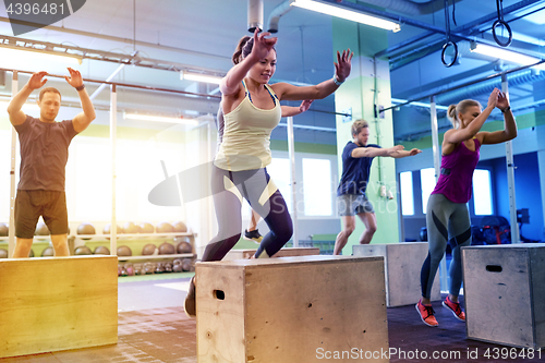 Image of group of people doing box jumps exercise in gym