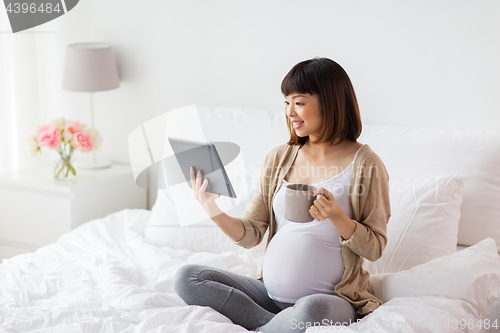 Image of happy pregnant asian woman with tablet pc at home