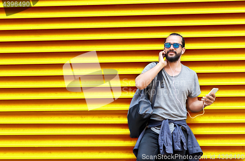 Image of man with earphones and smartphone over wall