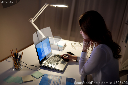 Image of businesswoman with laptop at night office