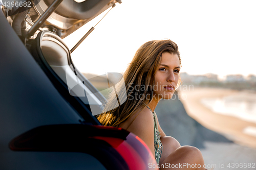 Image of Girl near the beach sitting on the car