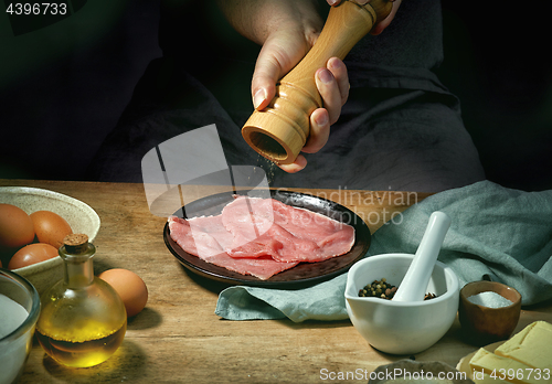 Image of cook is seasoning meat