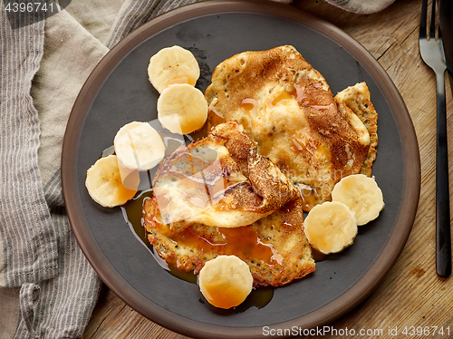 Image of Crepes with banana and caramel sauce on wooden desk