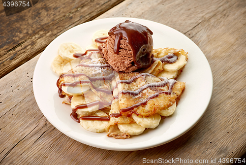 Image of Crepes with banana and chocolat icecream on wooden desk