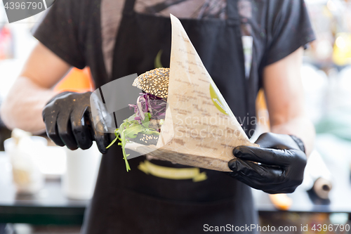 Image of Chef serving organic vegetarian fish burger at international urban street food festival.