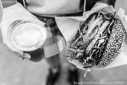 Image of Female Hands Holding Delicious Organic Salmon Vegetarian Burger and Homebrewed IPA Beer.