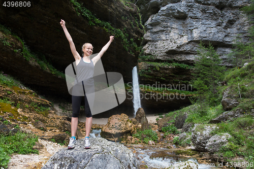 Image of Active woman raising arms inhaling fresh air, feeling relaxed in nature.