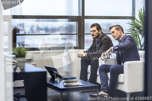 Image of Businessmen interviewing female candidate for job in modern corporate office.