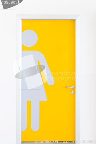 Image of Women symbols on yellow public toilet entrance door.