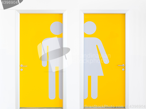 Image of Men and women symbols on yellow public toilet entrance doors.