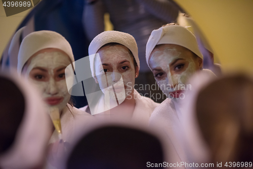 Image of women putting face masks in the bathroom