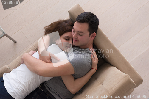 Image of young handsome couple hugging on the sofa