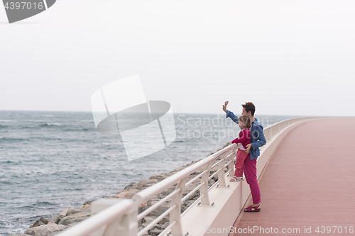 Image of mother and cute little girl on the promenade by the sea