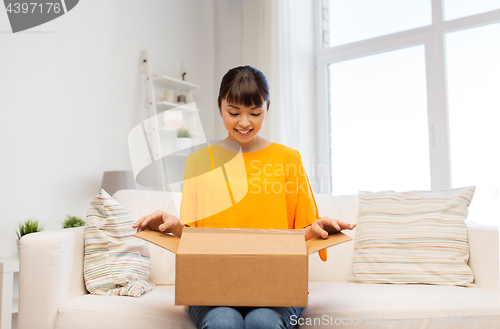 Image of happy asian young woman with parcel box at home