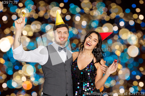 Image of happy couple with party blowers having fun