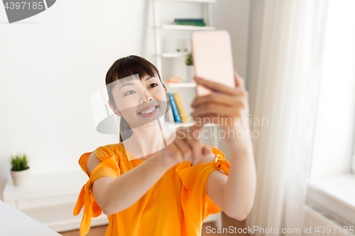Image of happy asian woman taking selfie by smartphone