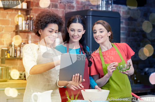 Image of happy women with tablet pc cooking in kitchen