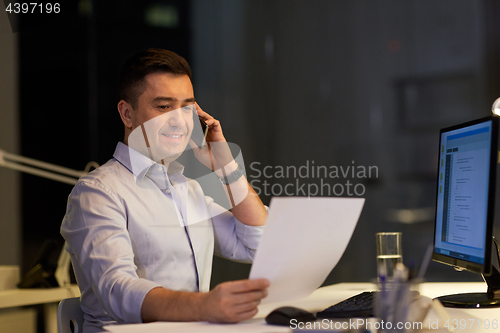 Image of businessman calling on sartphone at night office