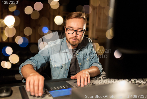 Image of man at mixing console in music recording studio