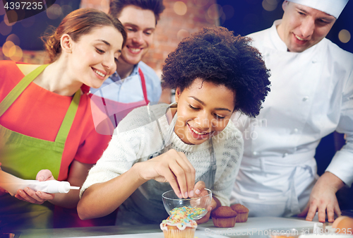 Image of happy friends and chef cook baking in kitchen