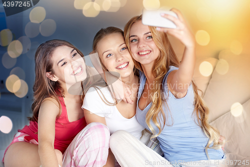 Image of teen girls with smartphone taking selfie at home