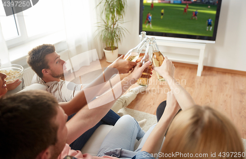 Image of friends clinking beer and watching soccer game