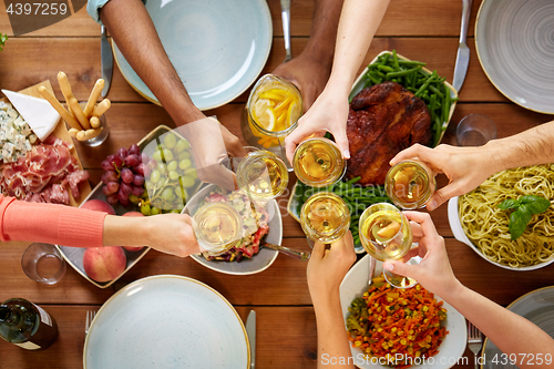 Image of hands clinking wine glasses over table with food