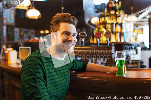 Image of man drinking green beer at bar or pub