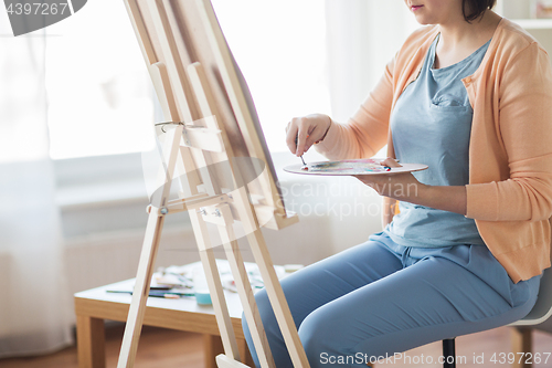 Image of artist with palette knife painting at art studio