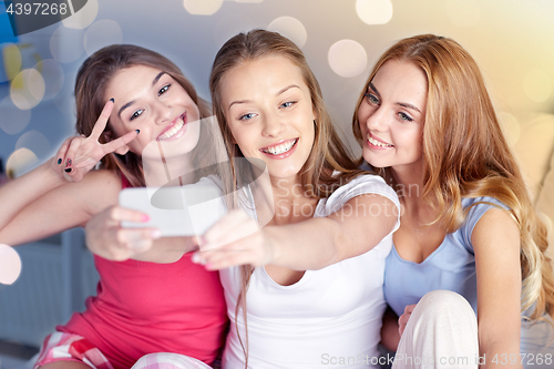 Image of teen girls with smartphone taking selfie at home