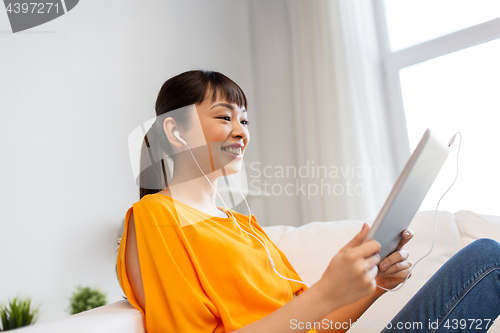 Image of happy asian woman with tablet pc and earphones