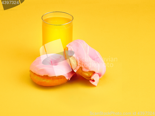 Image of The donuts and fresh orange juice on yellow background