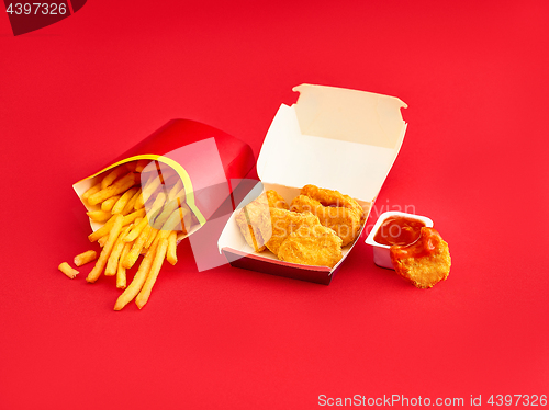 Image of chicken nuggets and french fries on red background