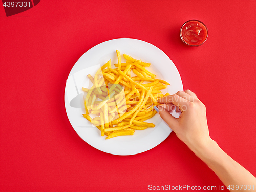 Image of Young woman eating french fries potato with ketchup in a restaurant
