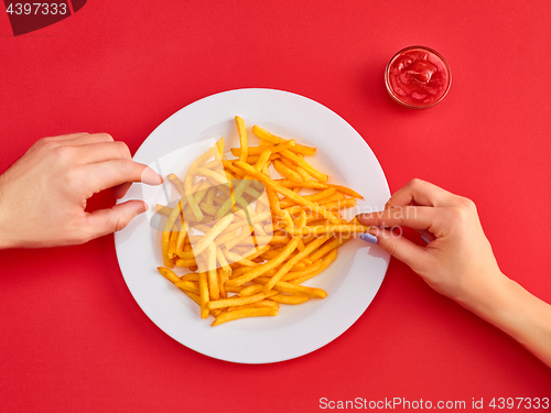 Image of Young woman eating french fries potato with ketchup in a restaurant