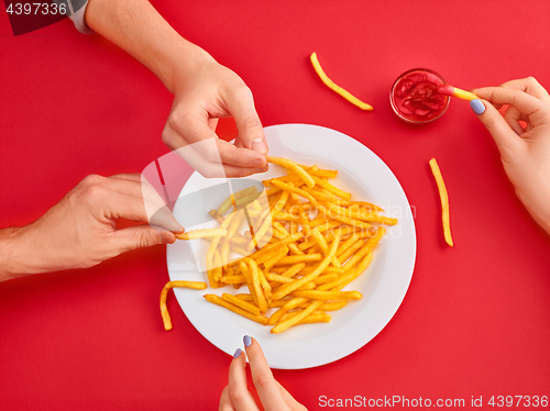 Image of Young woman eating french fries potato with ketchup in a restaurant