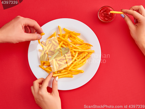 Image of Young woman eating french fries potato with ketchup in a restaurant