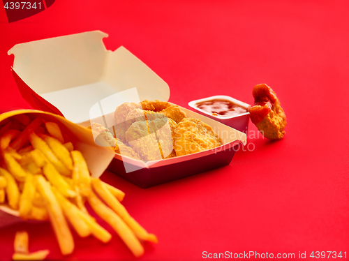 Image of chicken nuggets and french fries on red background