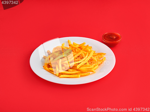 Image of French fries on a plate, isolated on red background