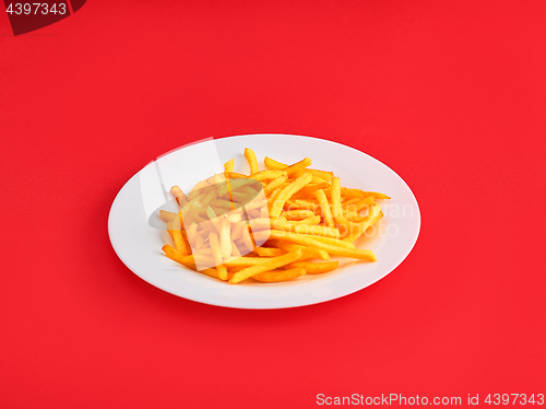 Image of French fries on a plate, isolated on red background