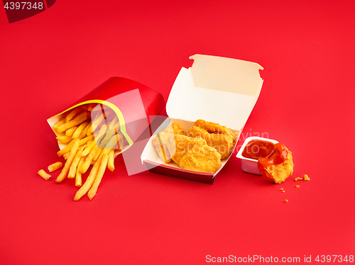 Image of chicken nuggets and french fries on red background