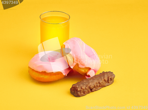 Image of The donuts and fresh orange juice on yellow background