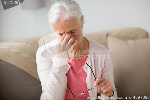 Image of senior woman with glasses having headache at home