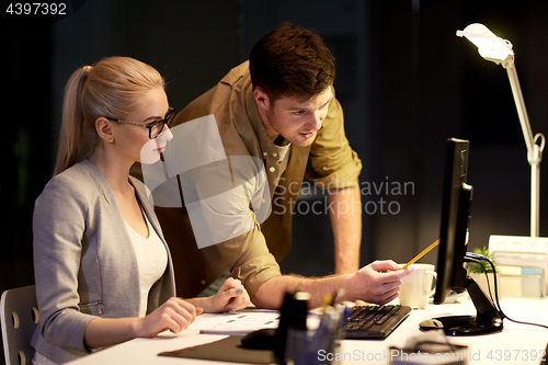 Image of business team with computer working late at office