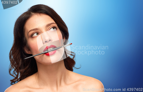Image of beautiful woman holding make up brush for lipstick