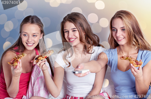 Image of happy friends eating pizza and watching tv at home