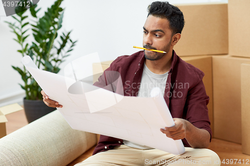 Image of man with blueprint and boxes moving to new home